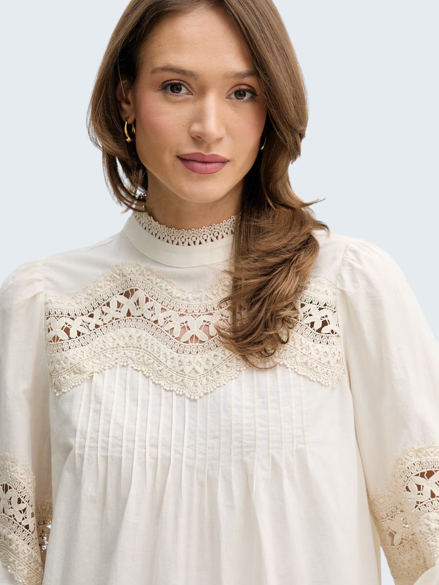 oui-ua.store cream cotton blouse with lace trim, pintuck details, and mock neck. Features a relaxed fit and button-back closure.