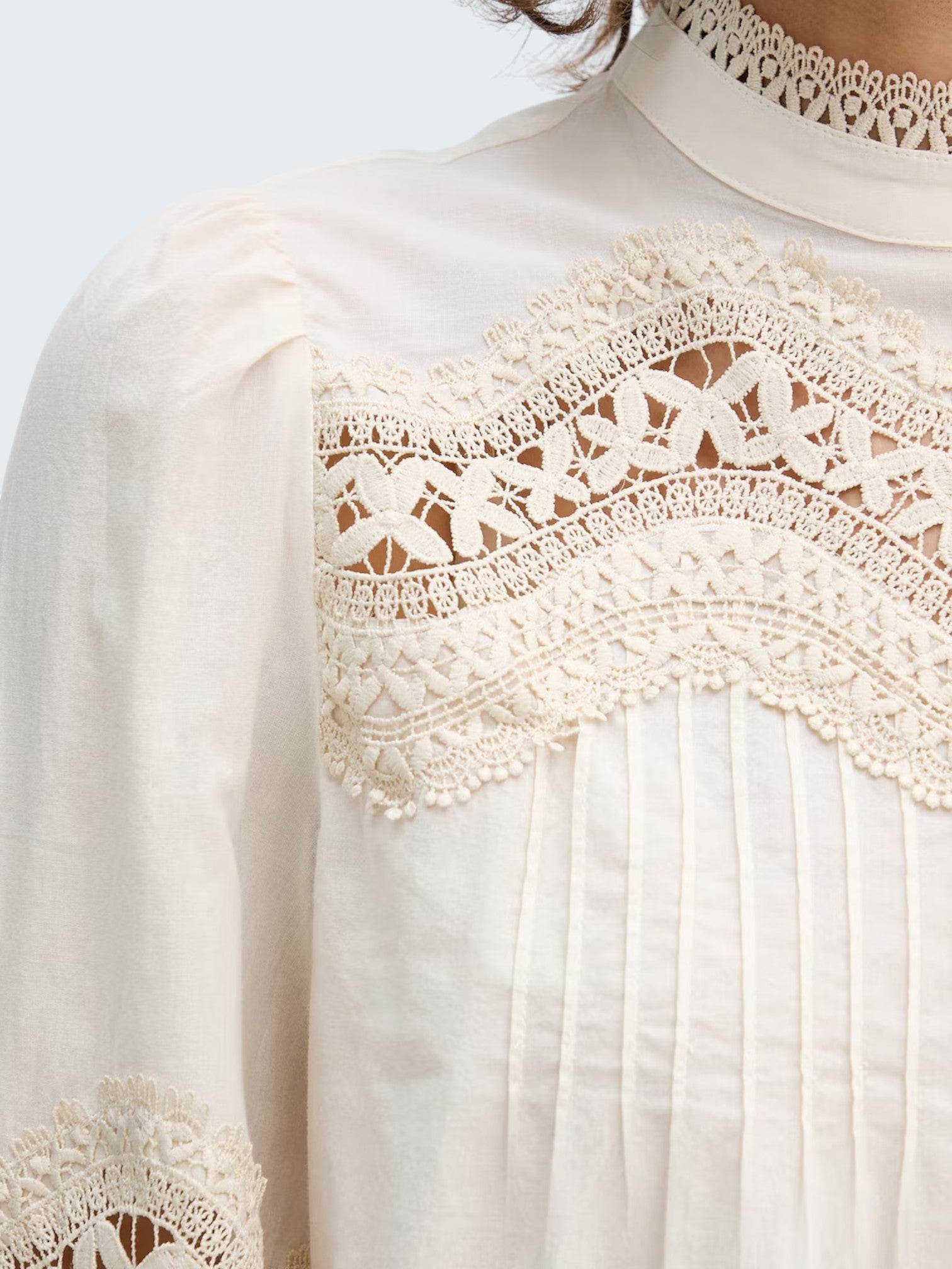 Oui-ua.store cream cotton blouse with intricate lace details, pintucks, and a stand collar. Features a relaxed fit and button-up back.