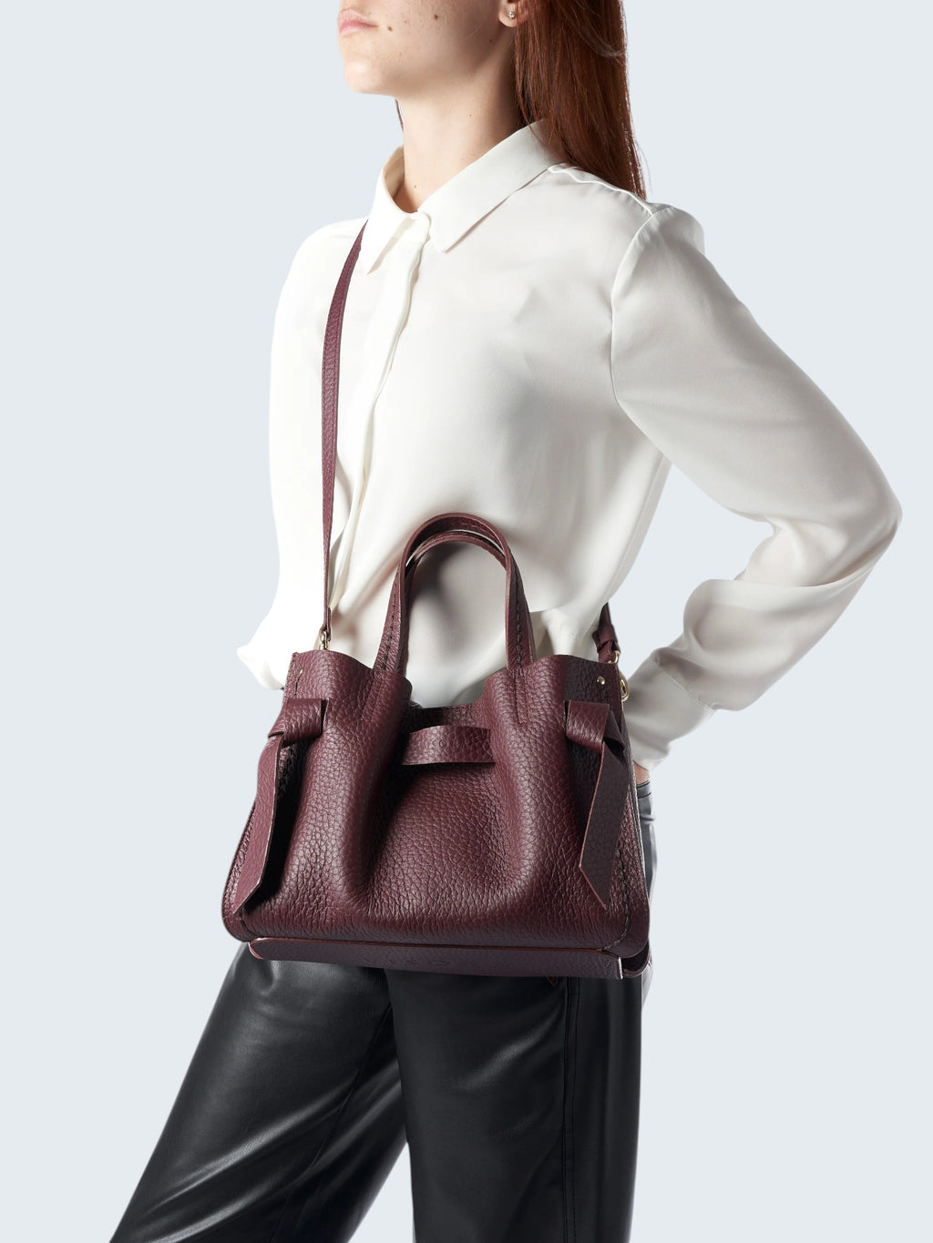 Oui-ua.store burgundy pebbled leather handbag with top handles and a detachable shoulder strap, worn by a model.